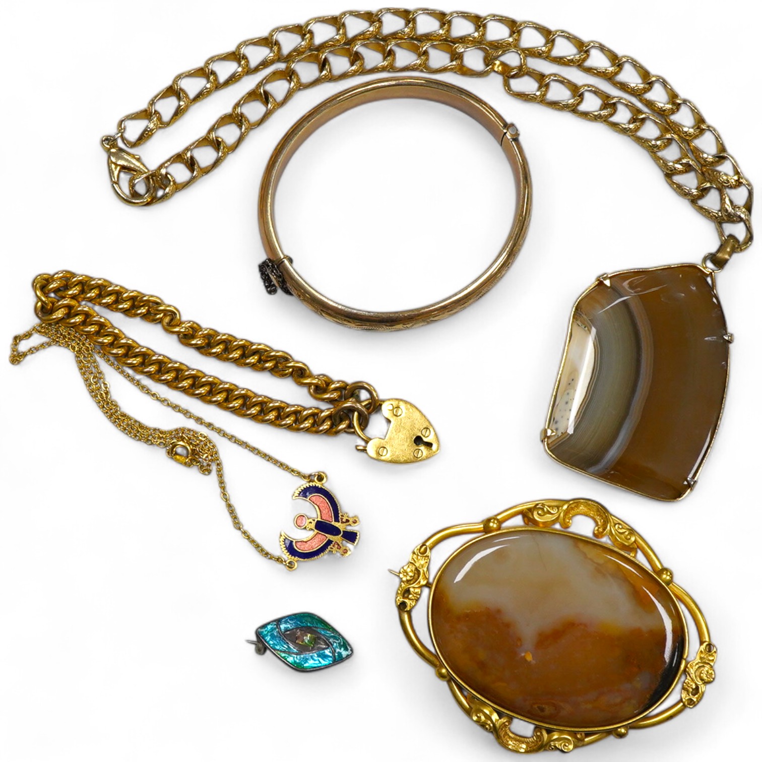 A group of gilt metal / pinchbeck jewels and an Arts & Crafts brooch by William Hair Haseler, comprising: a hinged bangle; an enamelled pendant in the Egyptian revival style; a gold curb link bracelet with a heart-shaped